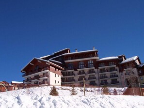 Um hotel com vários andares, varandas e uma pista de esqui em primeiro plano.