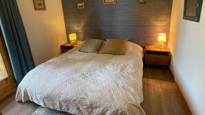 A neatly made bed with a patterned bedspread, two bedside tables with lamps, and a wooden headboard. - 3-room apartment for 6 in Méribel Altiport, near ski slopes (Méribel)