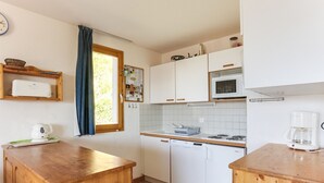 A compact kitchen with wooden cabinets, a microwave, a dishwasher, and a coffee maker. - Charming 4-room duplex, 8 people, west-facing terrace, near slopes (Peisey-Vallandry)