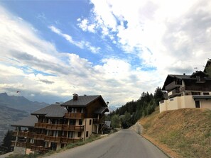 A mountain lodge with a wooden exterior, a balcony, and a view of the surrounding mountains. - Charming 4-room duplex, 8 people, west-facing terrace, near slopes (Peisey-Vallandry)