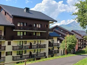 A multi-story hotel with balconies, a clear view of the mountains, and a paved driveway.