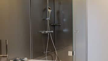 Un baño moderno con ducha de vidrio, una bañera independiente y un par de pantuflas en el suelo.