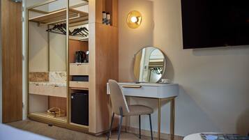A modern room with a built-in wardrobe, a desk with a chair, a flat-screen TV, and a mirror.