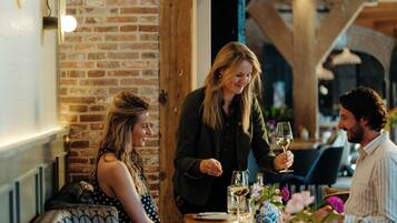 A restaurant with brick walls, wooden beams, and a table set with a vase of flowers.
