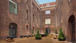 Un patio con muros de ladrillo, arcos y plantas en macetas.
