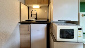 Une petite cuisine équipée d’un évier, d’un petit réfrigérateur et d’un four à micro-ondes.