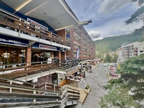 A multi-story hotel with a ski rental shop on the ground floor, balconies with bicycles, and a view of a mountainous area. - Cozy studio 2 sleeps near slopes in Vars Les Claux (Vars)