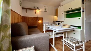 Une cuisine compacte comprenant une table à manger, des chaises et un réfrigérateur encastré.