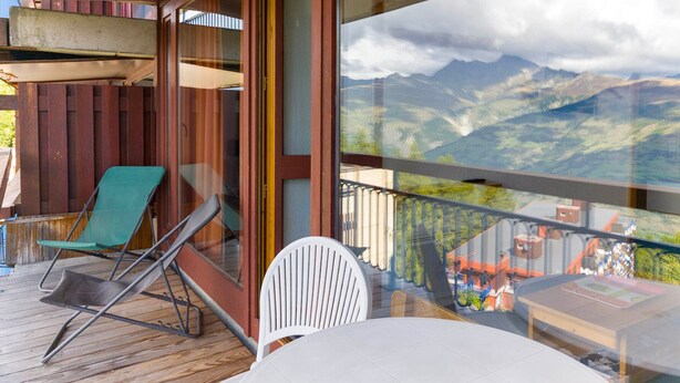 Un balcón con mesa y sillas, con vistas a un paisaje montañoso.