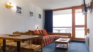 Una habitación acogedora con una mesa de comedor, sillas, un sofá y una mesita de noche con una lámpara.