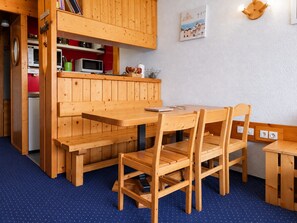 A wooden interior with a dining table and chairs, a bench, and a kitchenette area.
