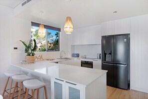 A modern kitchen with a central island, stainless steel appliances, and a view of the outdoors.