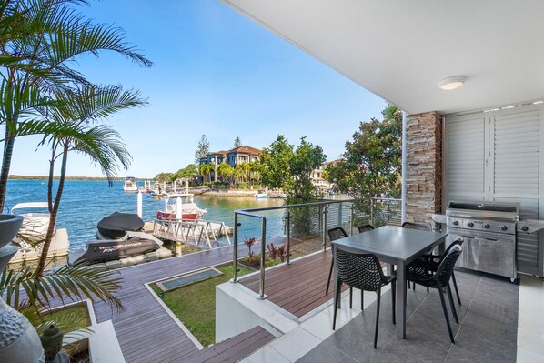 A balcony with a view of the sea, outdoor seating, and a barbecue area.