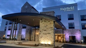 A Fairfield by Marriott hotel with a stone facade, a covered entrance, and a clear sky.