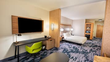 Quarto de hotel com cama, escrivaninha, cadeira, televisão e um pequeno armário.