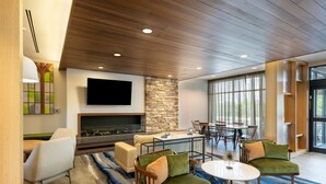 A modern living room with a stone fireplace, comfortable seating, a flat-screen TV, and large windows.