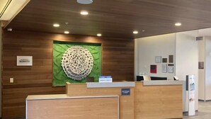 A hotel reception area with a wooden reception desk, a green wall with a circular design, and a sign that reads "Marriott Bonvoy".