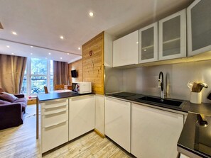 A compact kitchen with white cabinets, a black countertop, and a stainless steel sink.