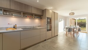 Una cocina moderna con electrodomésticos integrados, un comedor con mesa y sillas, y vistas al exterior.
