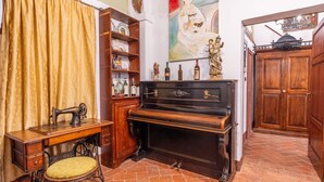 A vintage sewing machine, a wooden desk, a piano, and a painting on the wall. - Palazzo Danesi (Montepulciano)