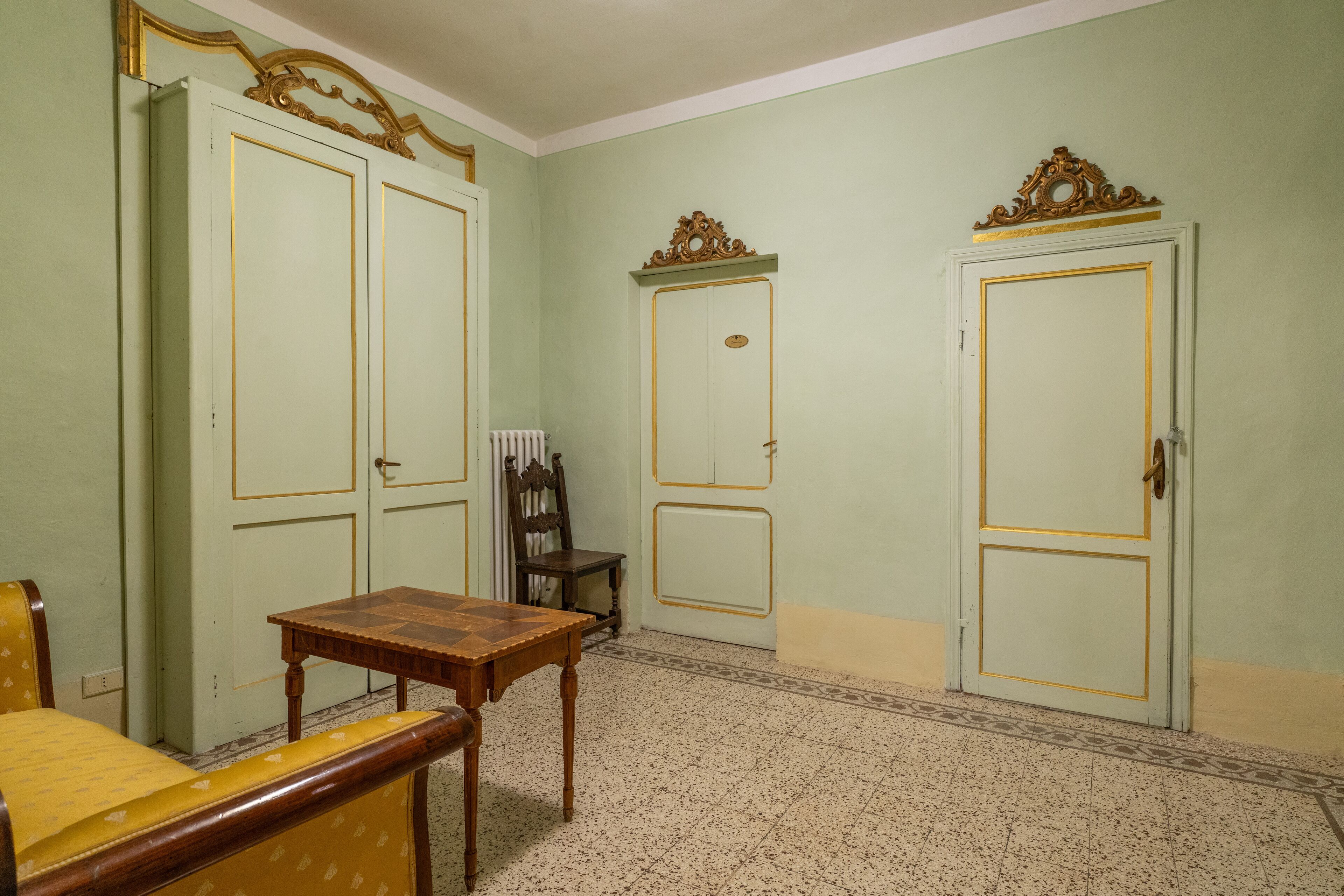 A room with two doors, a wooden table, a chair, and a radiator.