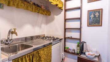 A kitchen with a stainless steel sink, a gas stove, and a wooden ladder leaning against the wall.