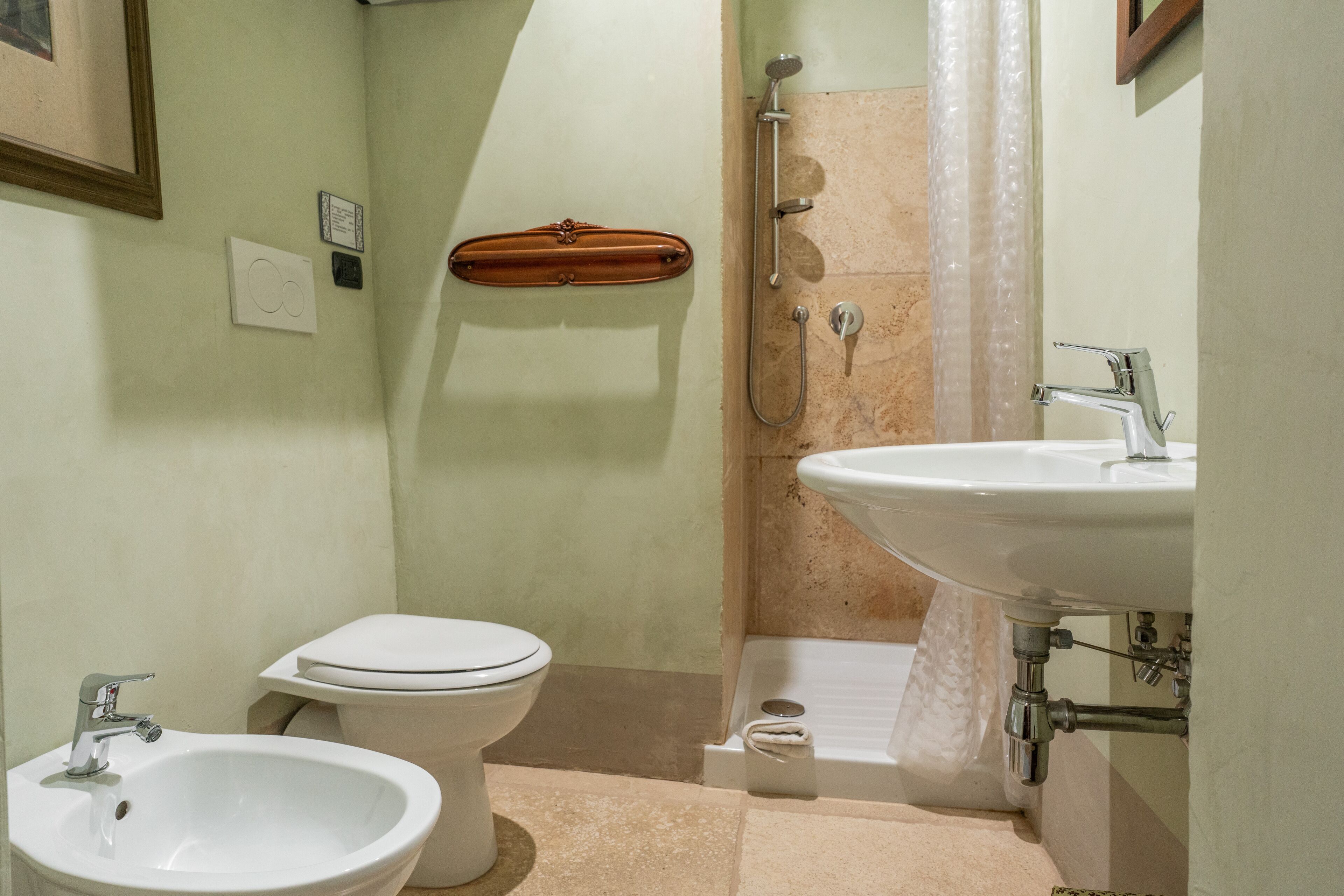 A bathroom with a sink, bidet, toilet, and shower.