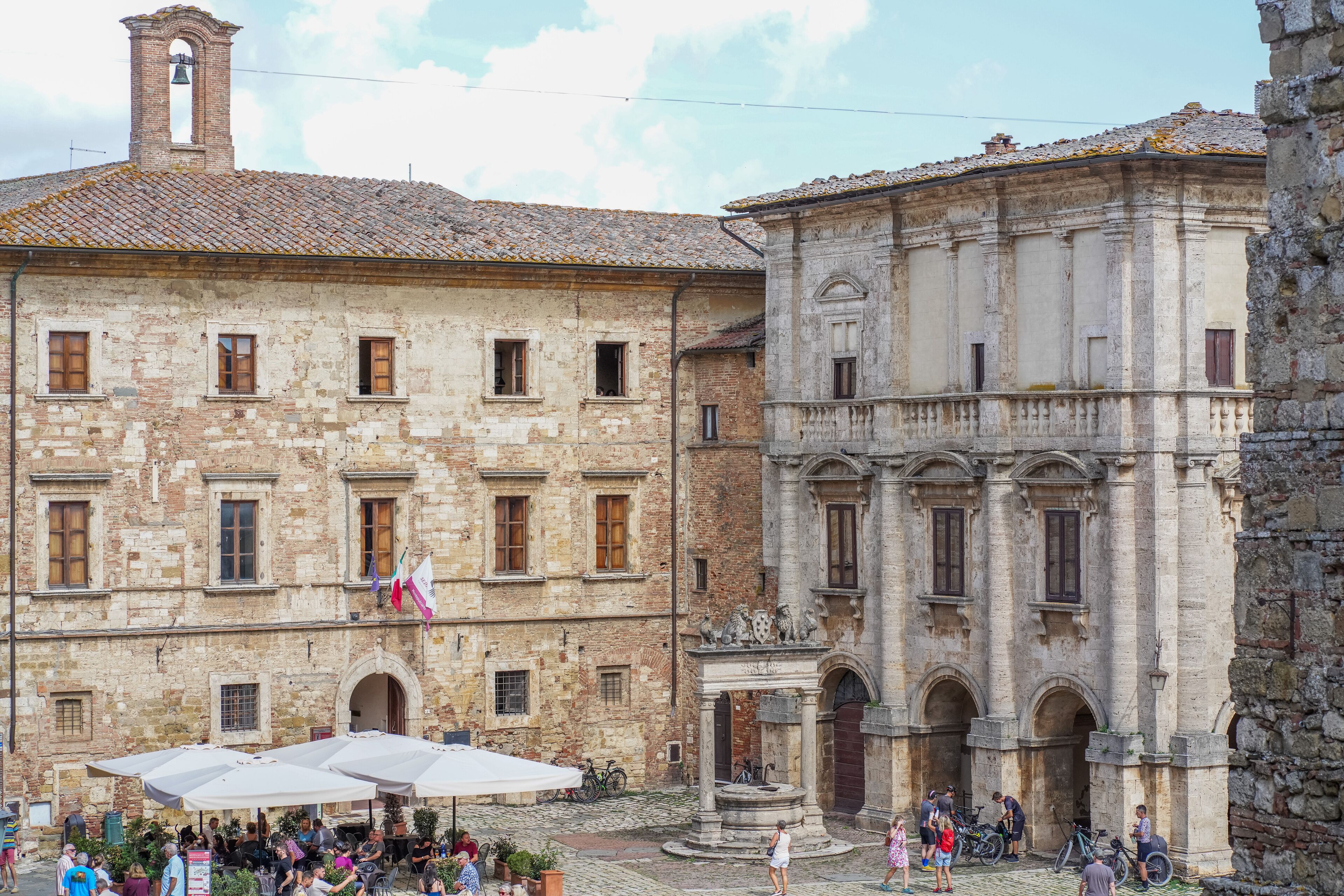 A historic building with a courtyard, featuring a fountain, outdoor seating, and bicycles.