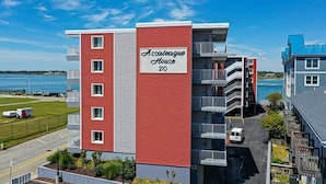 Un edificio de varios pisos con balcones, identificado como "Assateague House 210", cerca de una masa de agua.