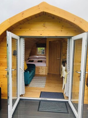 Cozy cabin with a bed, seating area, and window offering a view of the surrounding landscape.