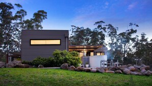 A modern house with a large window, surrounded by rocks and trees. - Kangary- secluded bush retreat with spa (Daylesford)