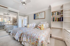 Une chambre avec deux lits, une bibliothèque et un ventilateur de plafond.