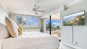 A bedroom with a bed, a ceiling fan, a TV, and a view of the ocean. - Unbeatable Ocean Vistas at Polo Beach Club #606 – Beachfront Living in Wailea (Makena, Maui)