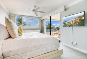 Ein Schlafzimmer mit Bett, Deckenventilator, Fernseher und Meerblick.