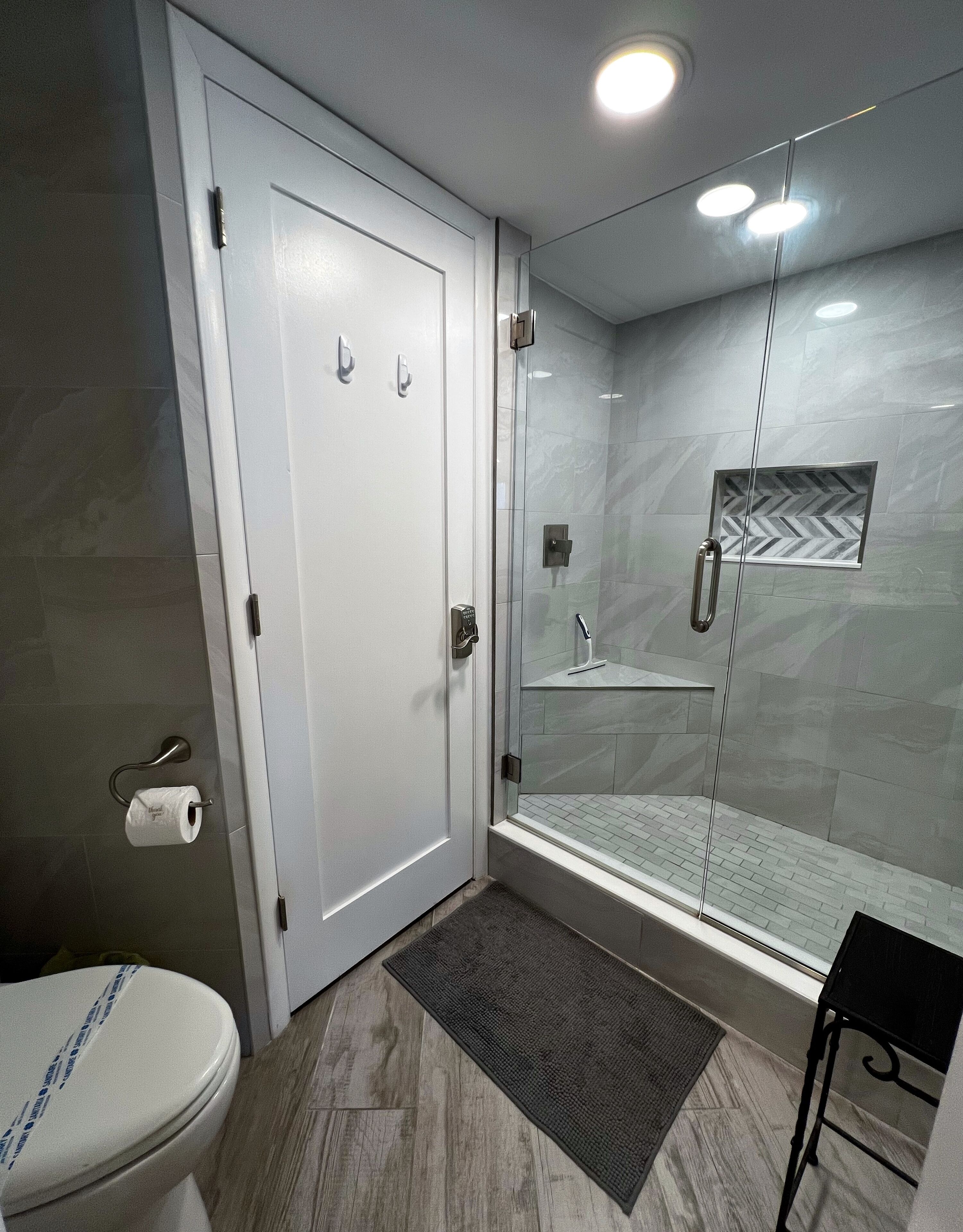 Un baño moderno con inodoro, ducha con mampara de vidrio y suelo de mármol.