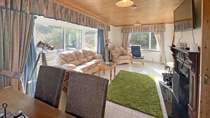 Ein gemütliches Wohnzimmer mit einer Couch, Sesseln, einem Couchtisch und einem Kamin.
