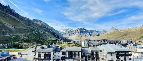 A modern town with a central road, buildings with flat roofs, and a mountainous backdrop.