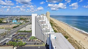 Un hotel di grandi dimensioni dal design moderno, situato accanto a una spiaggia con vista libera sull'oceano.