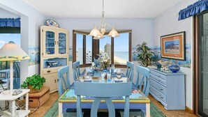 Zona pranzo con vista sulla spiaggia, un lampadario e un mobile con ante in vetro.
