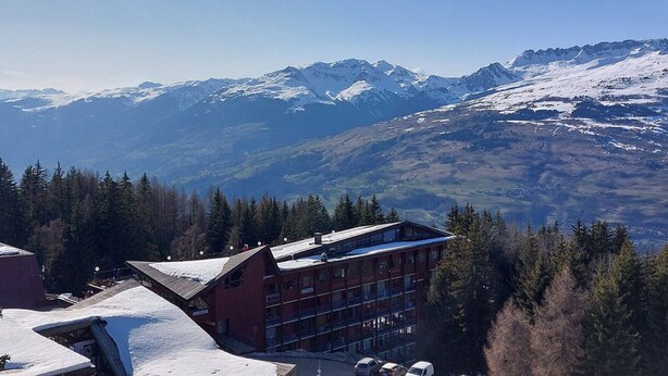 A hotel with a red building and a ski slope in the background. - Ski-in studio, pets allowed, Arc 1800 (Les Arcs 1800)