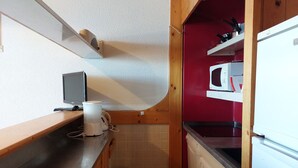 A compact kitchen with a microwave, a small sink, and a wooden countertop.