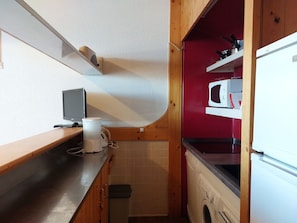 Une cuisine compacte équipée d’un four à micro-ondes, d’un petit évier et d’un plan de travail en bois.