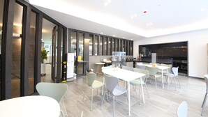 A modern kitchen with a large island, built-in appliances, and a dining area with light-colored chairs and a white table. - Hotel Stay Gumi (Gumi)