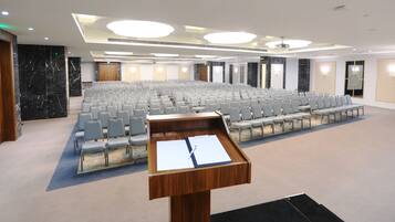 A conference room with rows of chairs, a podium, and a carpeted floor.
