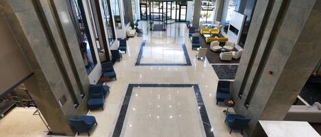 A spacious lobby with a central seating area, a fireplace, and a view of the outdoors.