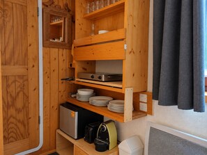 A compact kitchenette with wooden cabinets, a stove, and a small refrigerator.