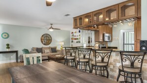 Un vaste espace de vie comprenant un coin repas avec une table et des chaises, un canapé et un coin cuisine doté de meubles en bois et d’un four à micro-ondes.