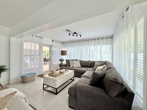 Ein Wohnzimmer mit einer Couch, einem Couchtisch und Blick durch große Fenster.