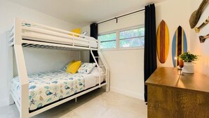 Habitación con literas, escritorio y tablas de surf en la pared.