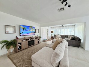 A living room with a television, sofa, and a patterned rug.